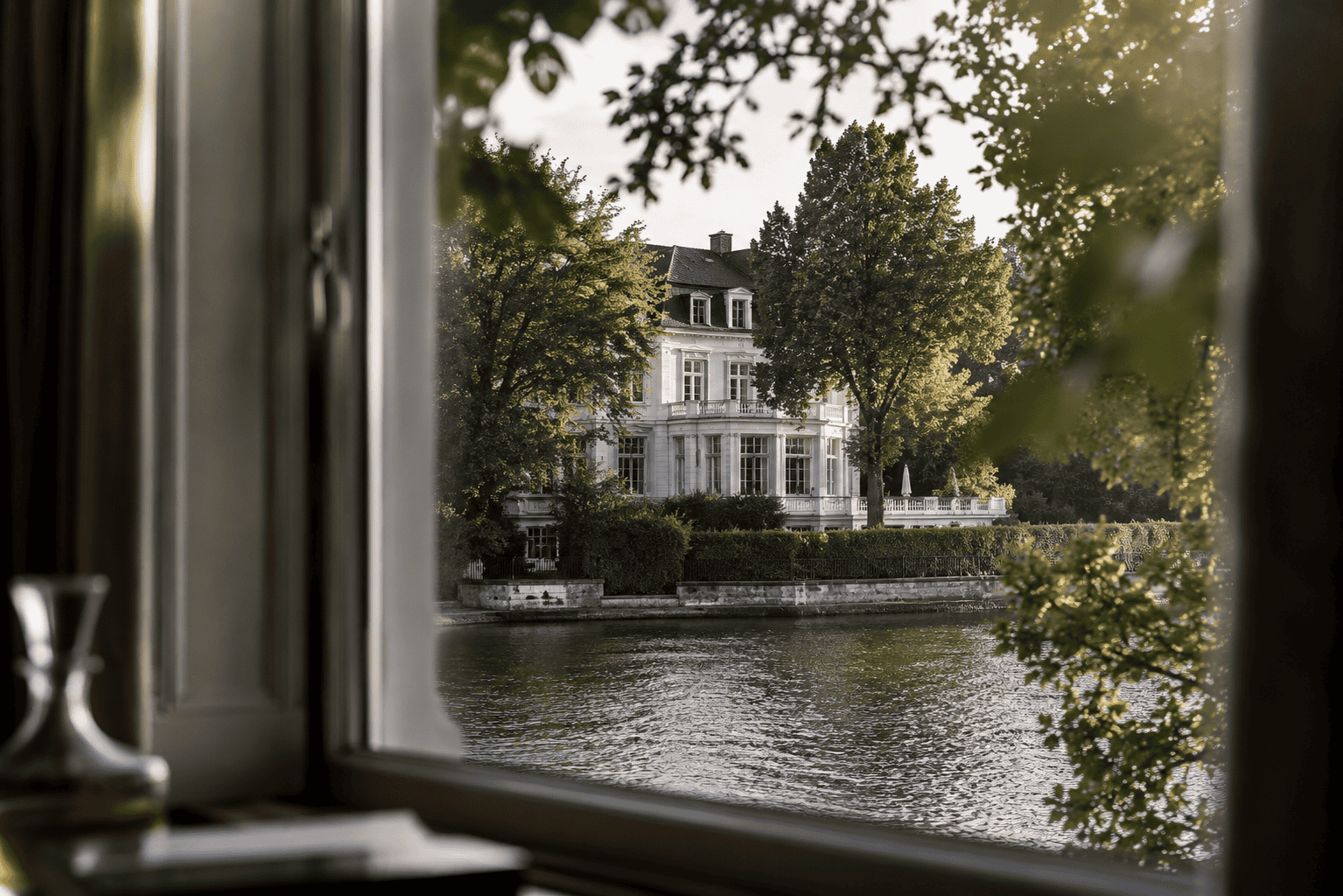 Luxusvilla am Wasser in Hamburg, Blick durch das Fenster auf den Fluss und die elegante Architektur.