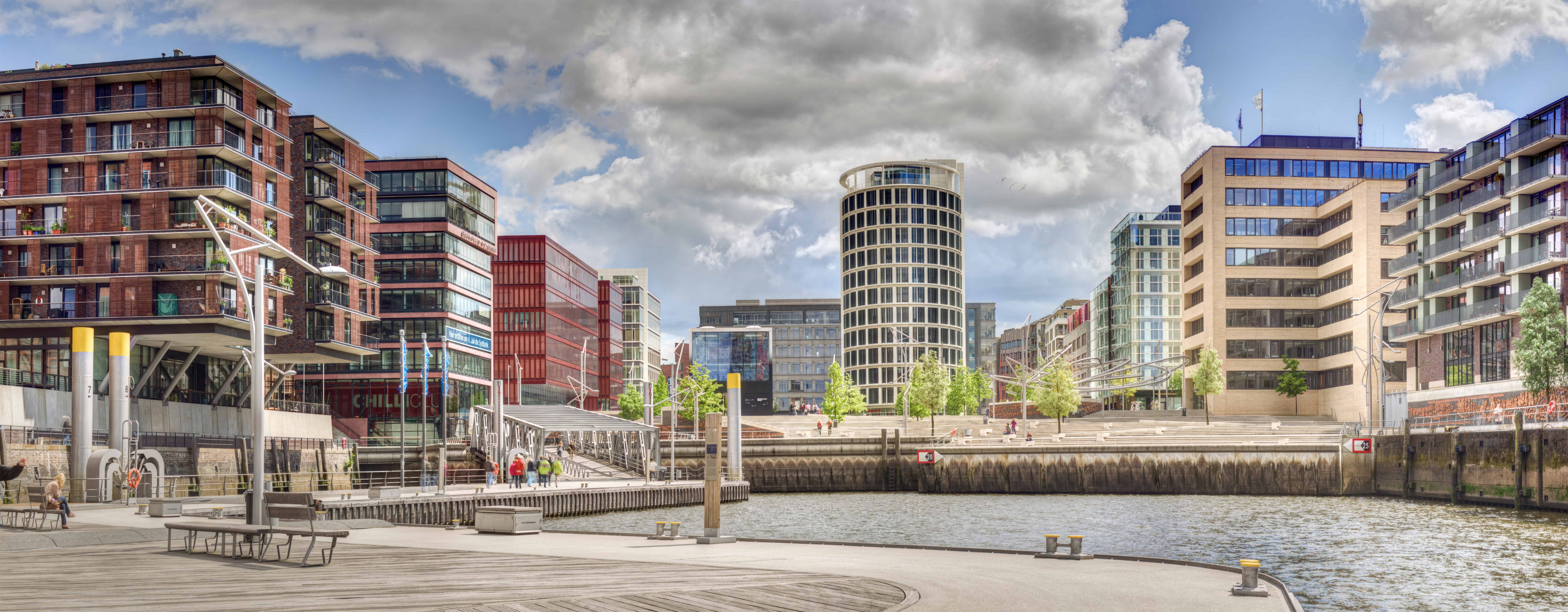 Hafen Hamburg mit modernen Bürogebäuden und Wasserfront, Stadtansicht bei bewölktem Himmel.