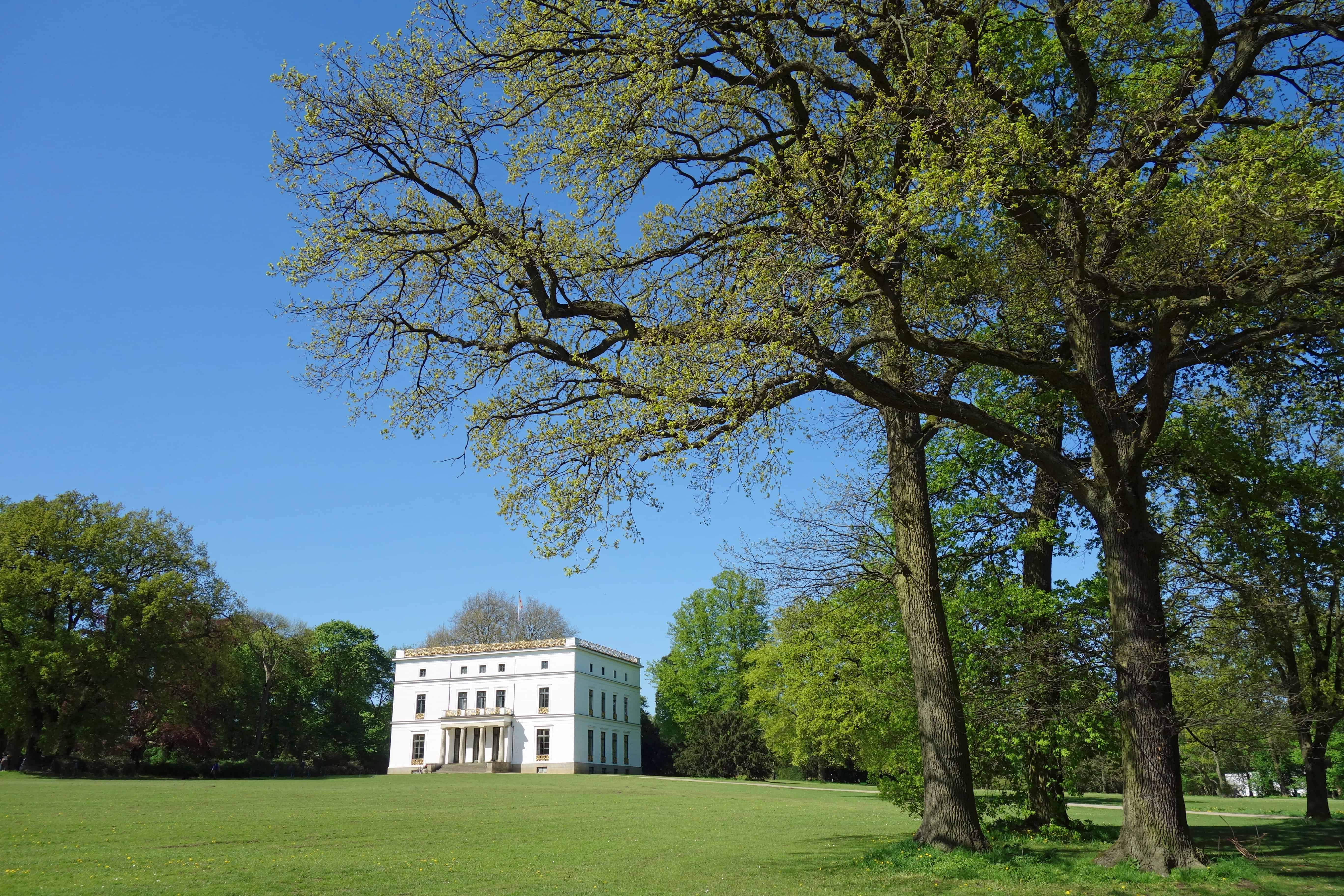 Hochwertiges Herrenhaus im Grünen mit großen Bäumen und gepflegtem Rasen in Hamburg.