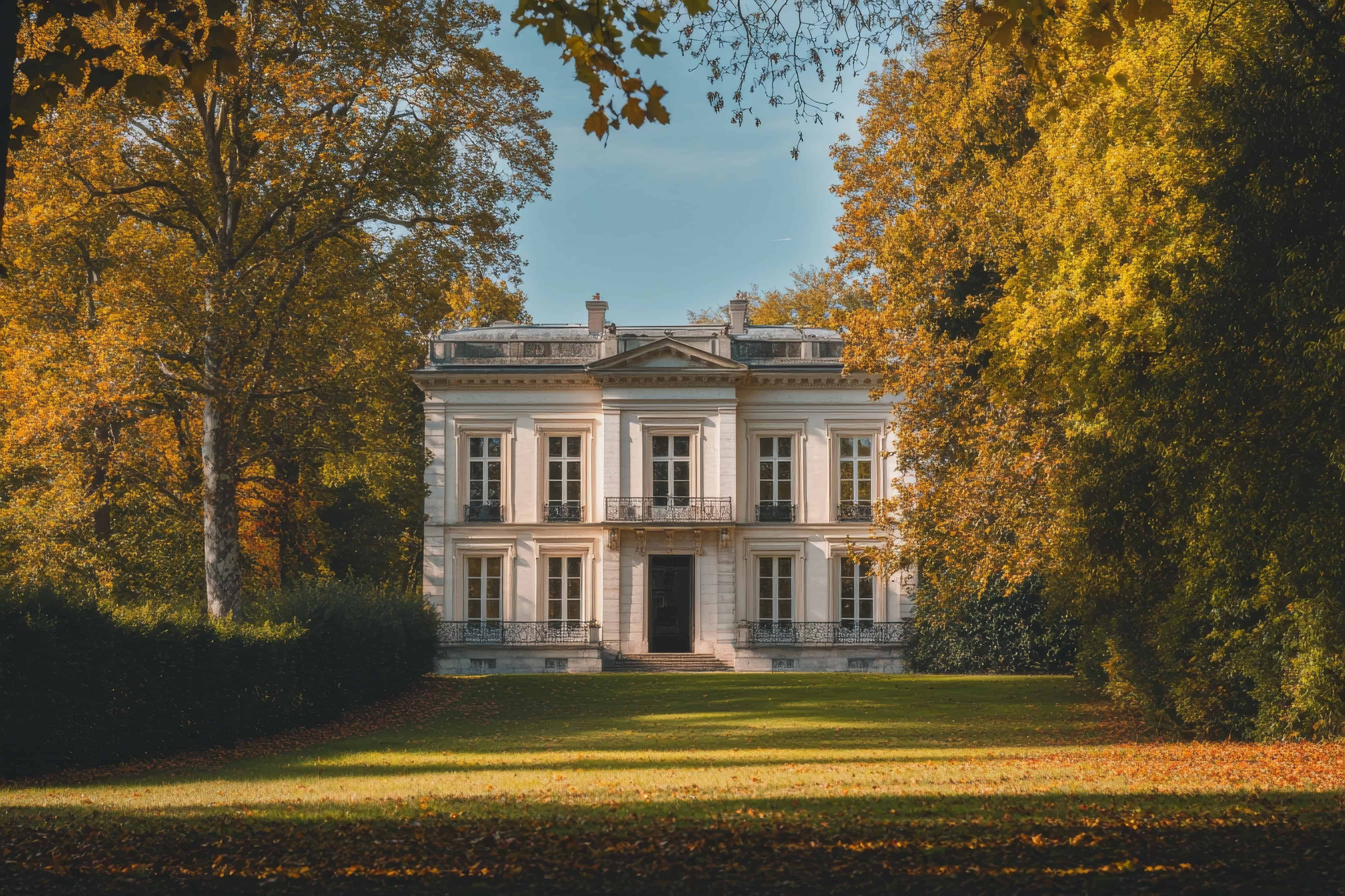 Elegantes Herrenhaus im Herbst mit goldenen Blättern und gepflegtem Garten.