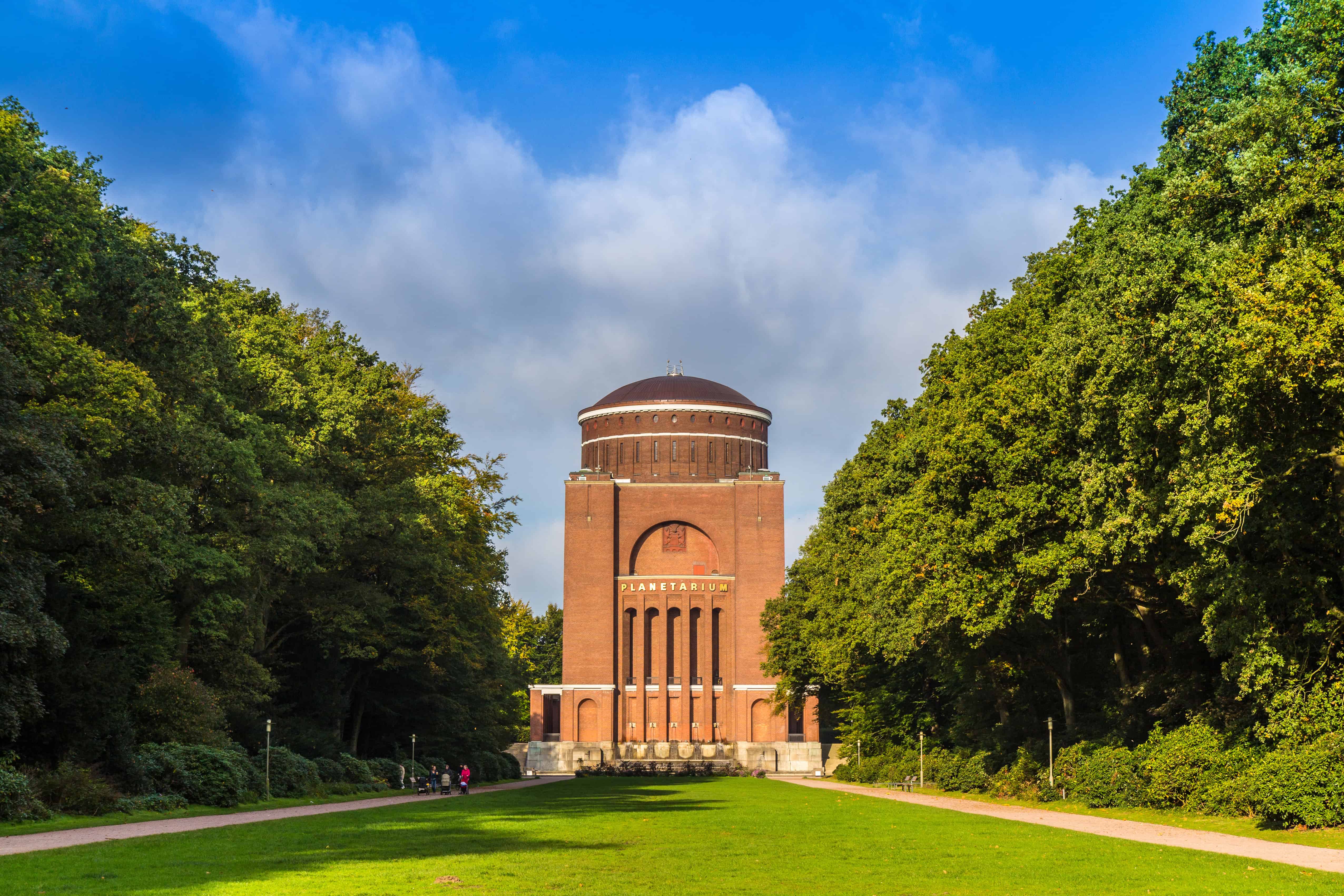 Hochbunker im Park mit grüner Wiese und Baumreihen, Hamburg, Deutschland.