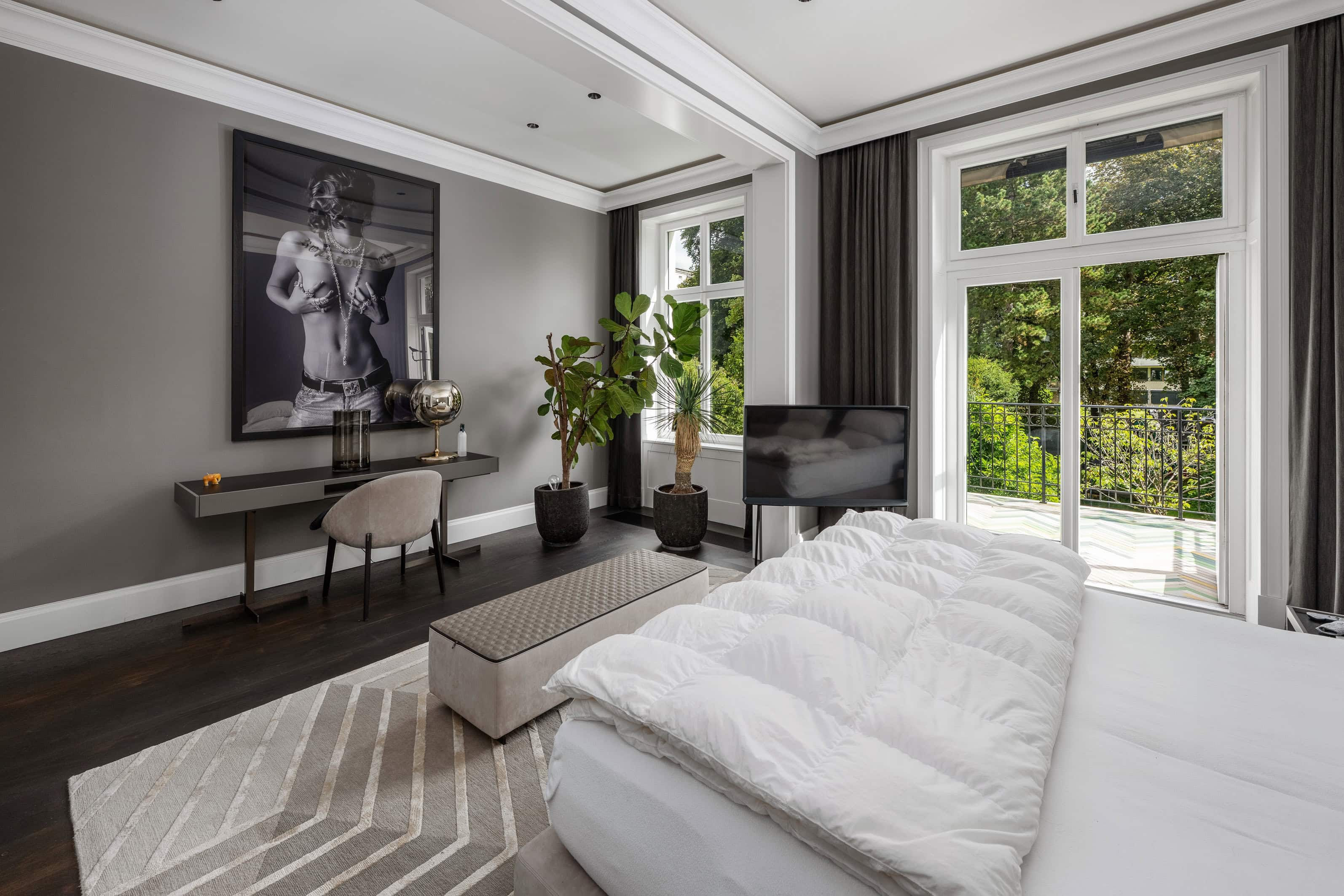 Helles Schlafzimmer mit großen Fenstern und Blick auf grüne Natur.