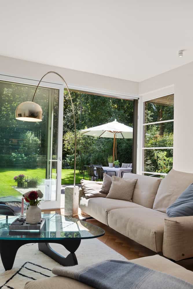 Modernes Wohnzimmer mit großen Fenstern und Blick auf Garten und Terrasse.