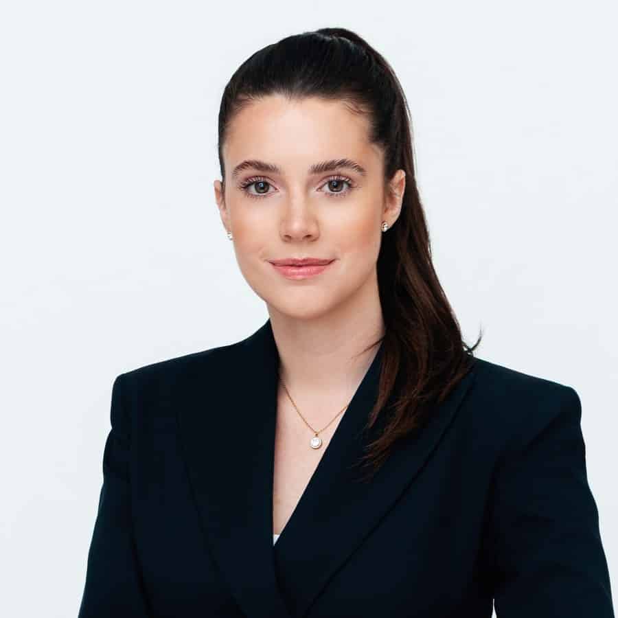 Professionelles Porträt einer Frau in dunklem Blazer vor weißem Hintergrund.