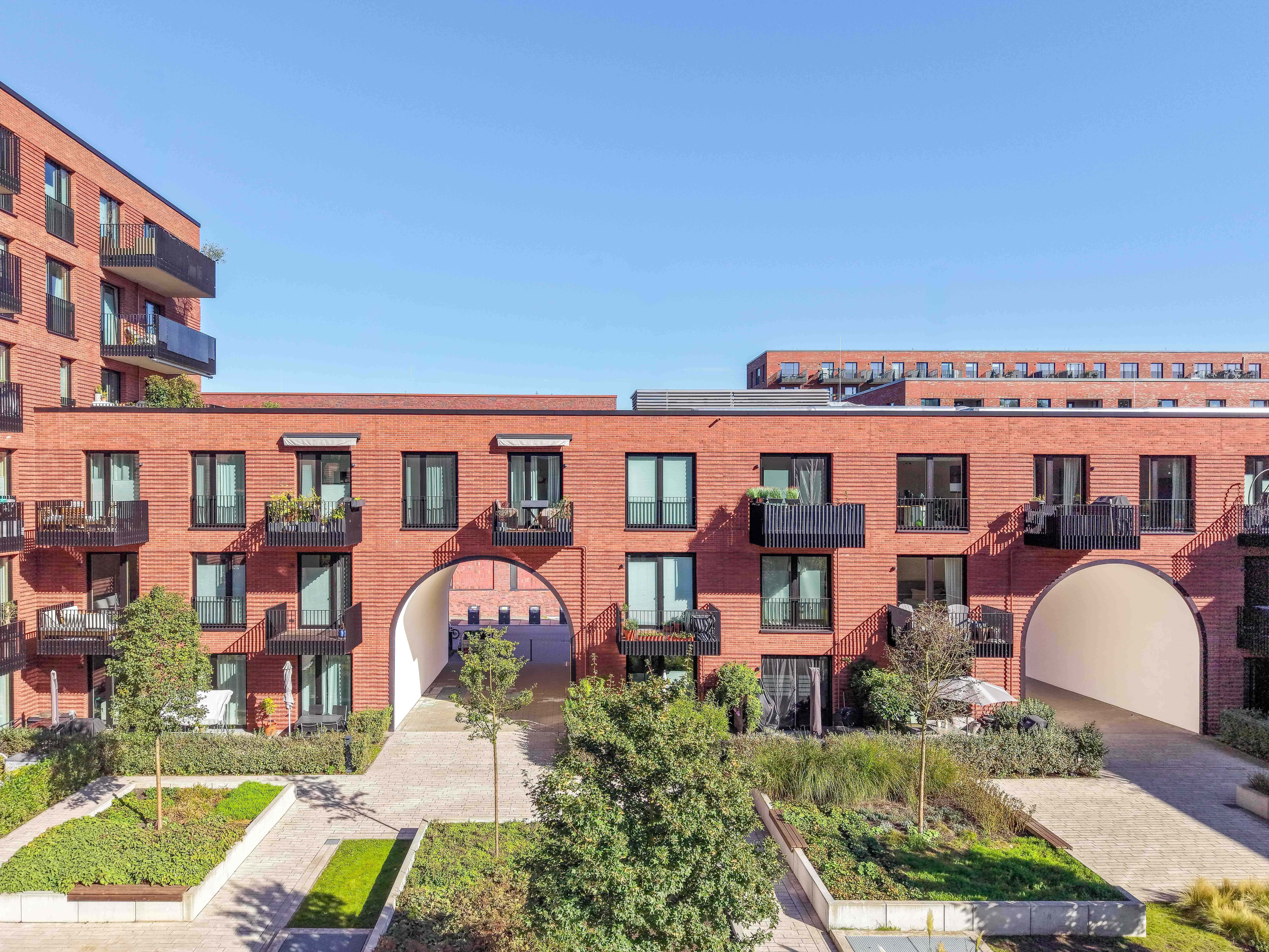 Moderne Wohnanlage mit Balkonen und Garten in Hamburg.