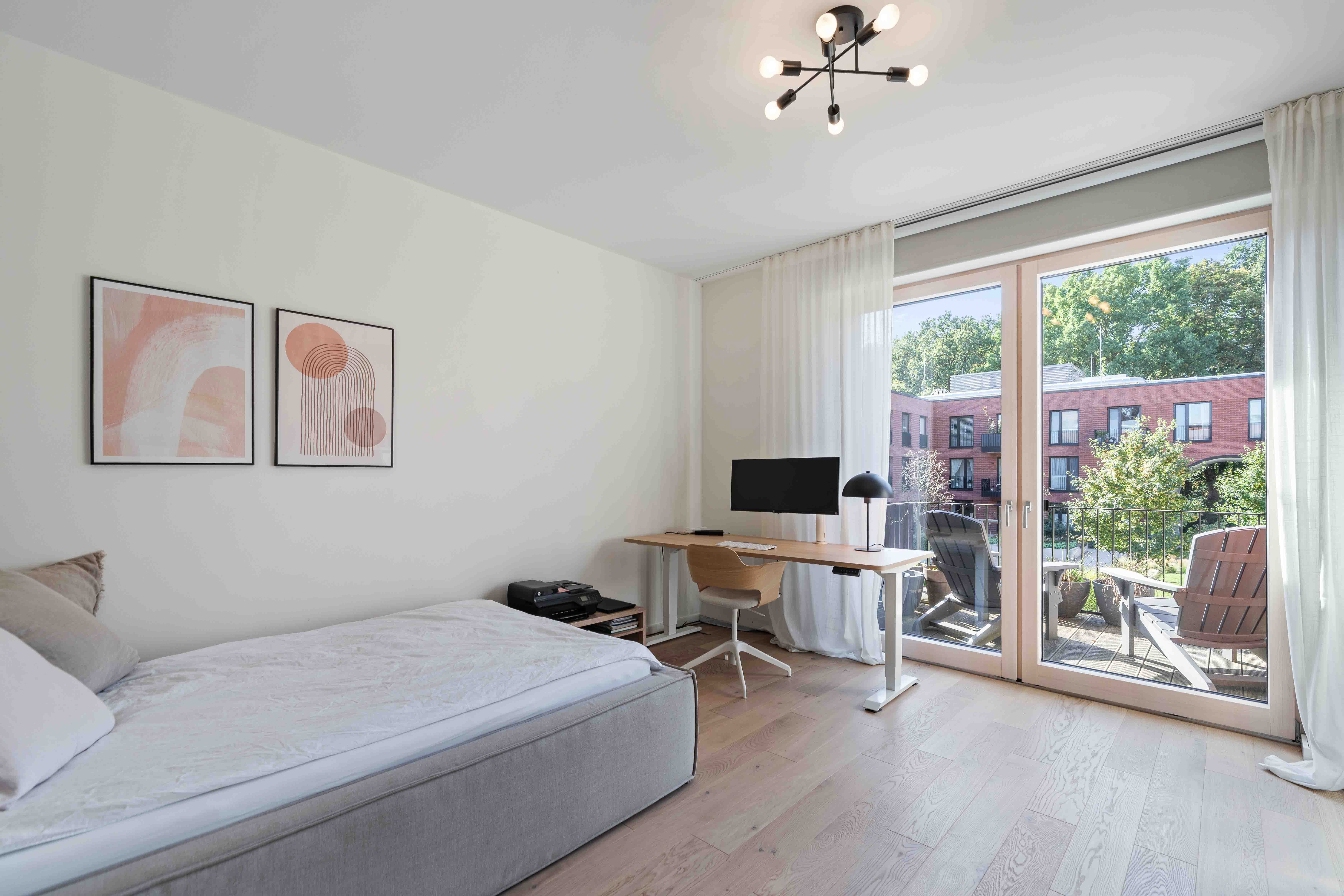 Helles Schlafzimmer mit Balkon und Blick auf grüne Bäume in Hamburg.
