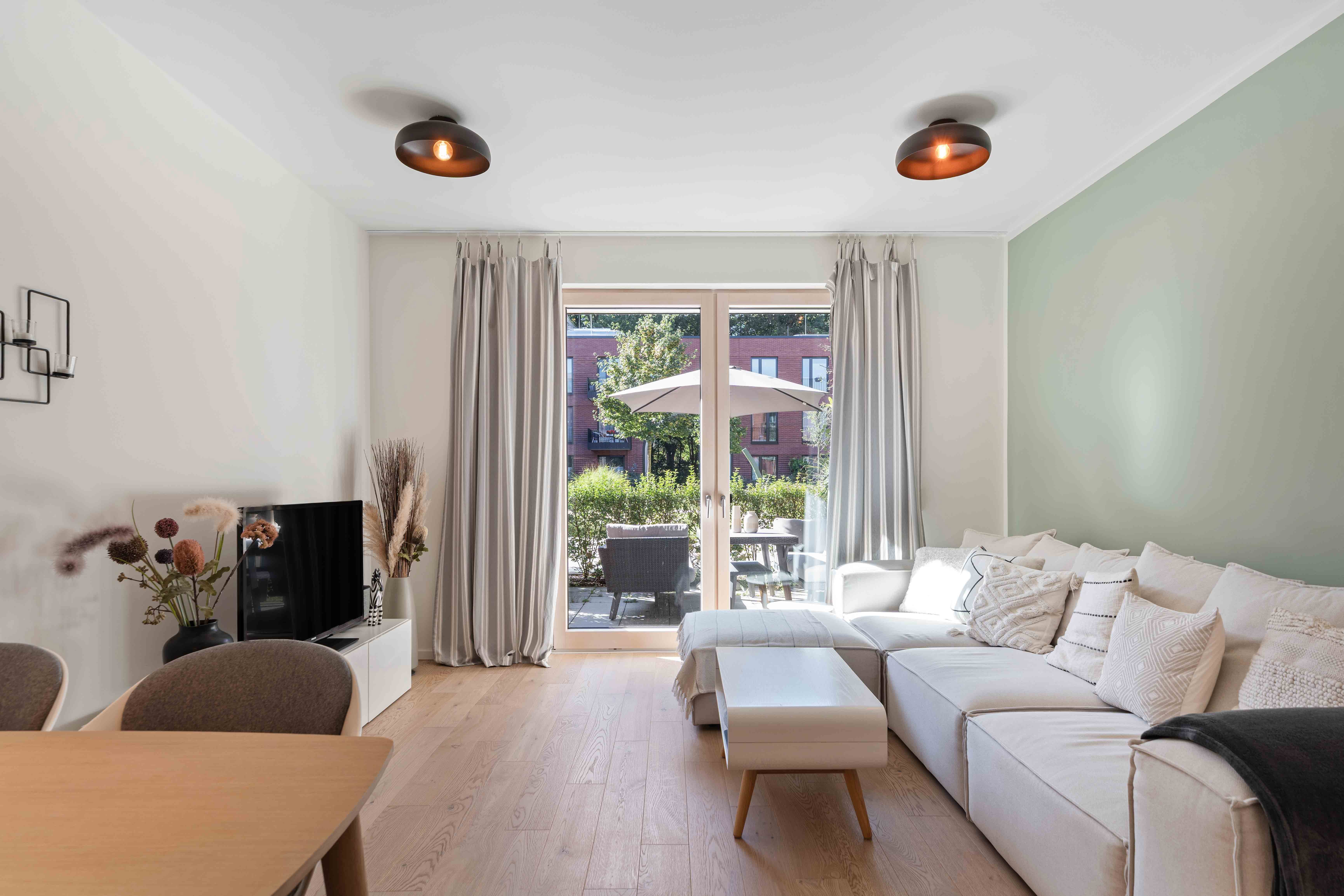 Gemütliches Wohnzimmer mit großen Fenstern und Balkonzugang.